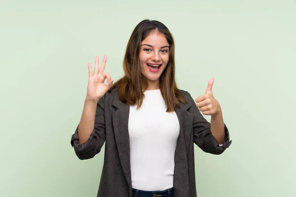 Jong Brunette Meisje Met Blazer Geïsoleerde Groene Achtergrond Tonen Teken — Stockfoto