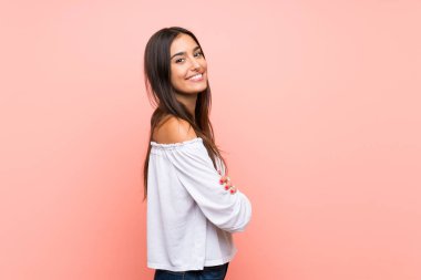 Kollarını kavuşturup ileriye bakan pembe bir geçmişi olan genç bir kadın.
