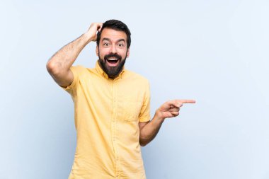 Mavi arka planda sakallı genç adam şaşırdı ve parmağını yana çevirdi.