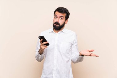 El kaldırırken cep telefonu tutan sakallı genç bir adam.