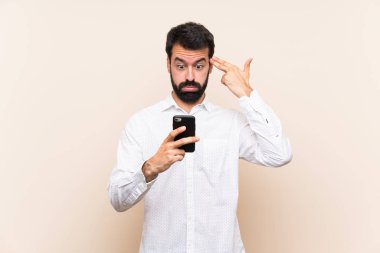 Sakallı genç bir adam cep telefonu tutuyor ve intihar jesti yapıyor.