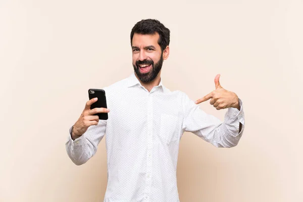 Junger Mann Mit Bart Hält Ein Handy Stolz Und Selbstzufrieden — Stockfoto