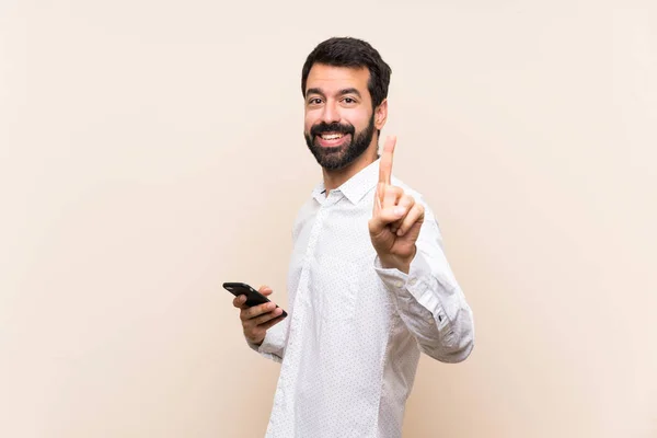 Joven Con Barba Sosteniendo Móvil Mostrando Levantando Dedo —  Fotos de Stock