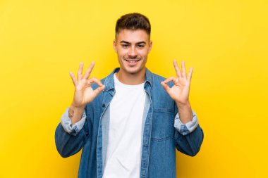 Izole sarı arka plan üzerinde genç yakışıklı adam parmakları ile ok işareti gösteren