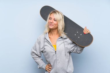 Sarışın genç bir kadın, izole edilmiş bir geçmişi var, kaykay yapıyor ve etrafına bakıyor.