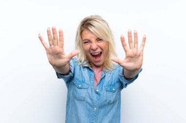 İzole edilmiş beyaz arka planı olan genç sarışın kadın parmaklarıyla 10 'a kadar sayıyor.