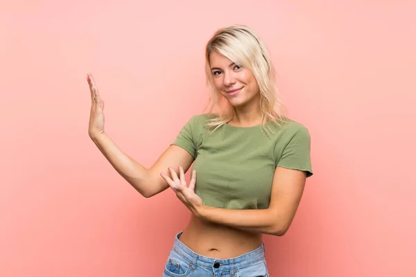 Jonge Blonde Vrouw Geïsoleerde Roze Achtergrond Reikende Handen Aan Zijkant — Stockfoto