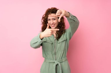 Soyutlanmış pembe arka plan odaklanan genç ve güzel bir kadın. Çerçeve sembolü