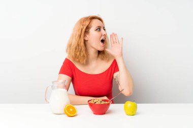 Kahvaltı yapan genç bir kadın ağzı açık bağırıyor.