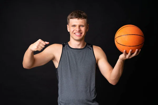 Pemuda tampan bermain basket di atas dinding hitam yang terisolasi — Stok Foto