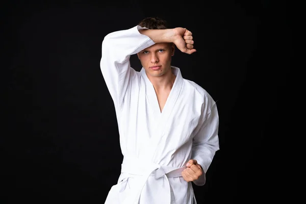 Młody człowiek robi karate na odizolowanym czarnym tle — Zdjęcie stockowe