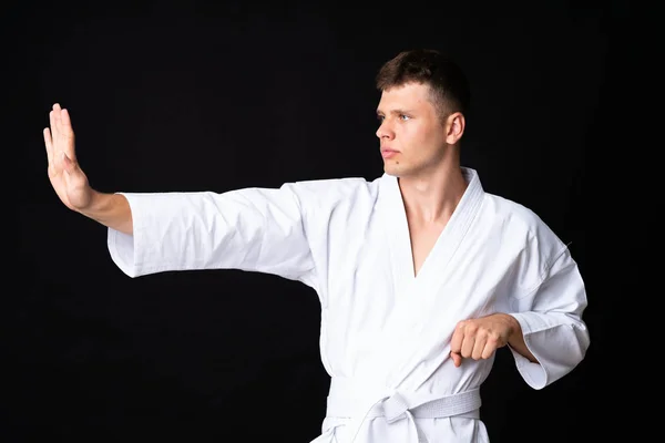 Mladý muž dělá karate přes izolované černé pozadí — Stock fotografie