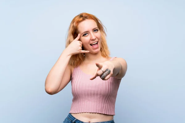 Jonge Vrouw Geïsoleerde Blauwe Achtergrond Maken Telefoon Gebaar Wijzen Naar — Stockfoto