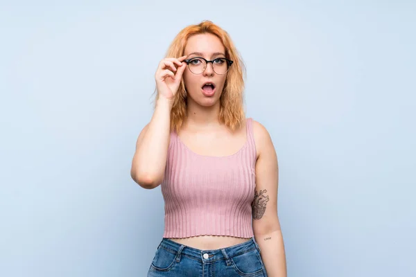 Mujer Joven Sobre Fondo Azul Aislado Con Gafas Sorprendida — Foto de Stock