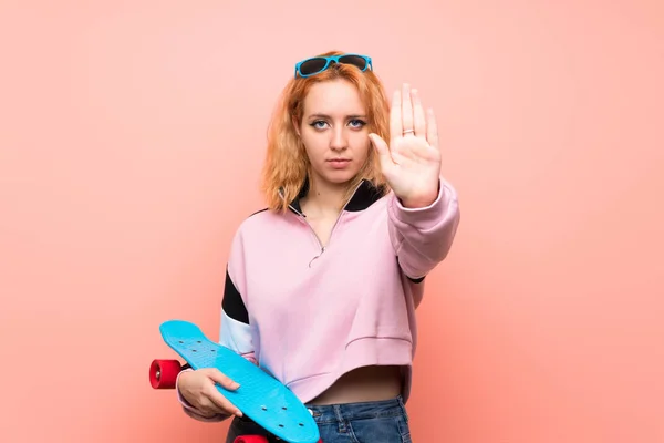 若いですスケーター女性以上隔離されたピンクの背景作りストップジェスチャーとともに彼女の手 — ストック写真
