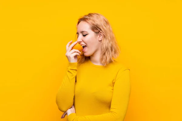 Młoda kobieta trzymanie pomarańczy na białym tle żółtym — Zdjęcie stockowe