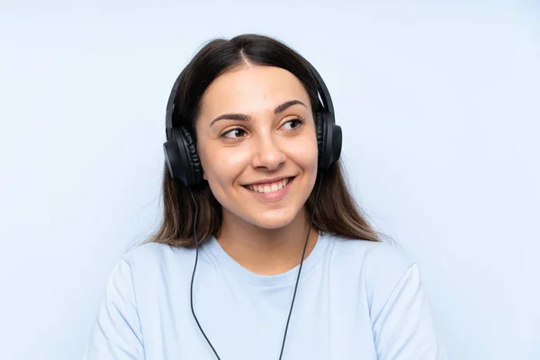 Mujer Joven Escuchando Música Sobre Fondo Azul Aislado Mirando Hacia —  Fotos de Stock