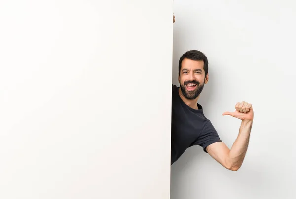 Joven hombre guapo con barba sosteniendo un gran cartel vacío —  Fotos de Stock