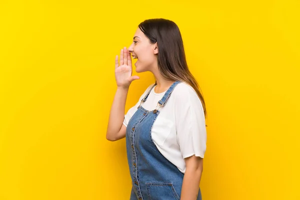 Mujer Joven Dungarees Sobre Fondo Amarillo Aislado Gritando Con Boca — Foto de Stock