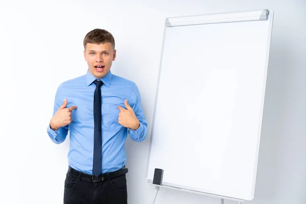 Young businessman giving a presentation on white board with surprise facial expression