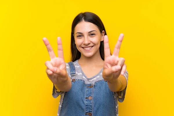 Mujer Joven Dungarees Sobre Fondo Amarillo Aislado Sonriendo Mostrando Signo —  Fotos de Stock