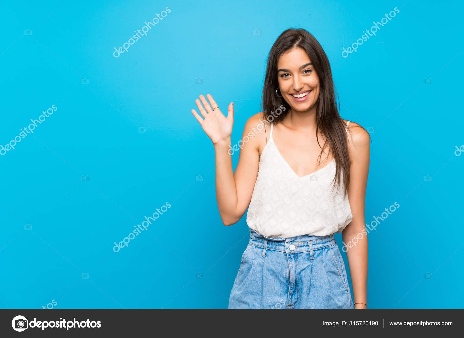年轻女子在孤寂的蓝色背景上带着快乐的表情举手敬礼 图库照片 C Luismolinero 年轻女子在孤寂的蓝色背景上带着快乐的表情举手敬礼 图库照片 C Luismolinero