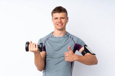 Ağırlık kaldıran genç sporcu, izole edilmiş beyaz duvarın üzerinden başparmak kaldırıyor. Çünkü iyi bir şey oldu.