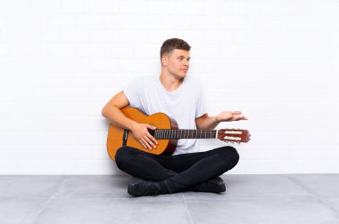 Gitarlı yakışıklı ve yüzünde sürpriz ifade olan genç bir adam.