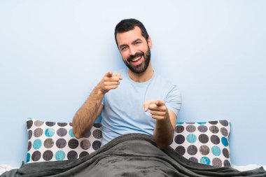 Yataktaki adam gülümserken seni işaret ediyor.