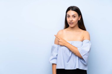 Izole mavi arka plan yan parmak işaret üzerinde Genç esmer kadın