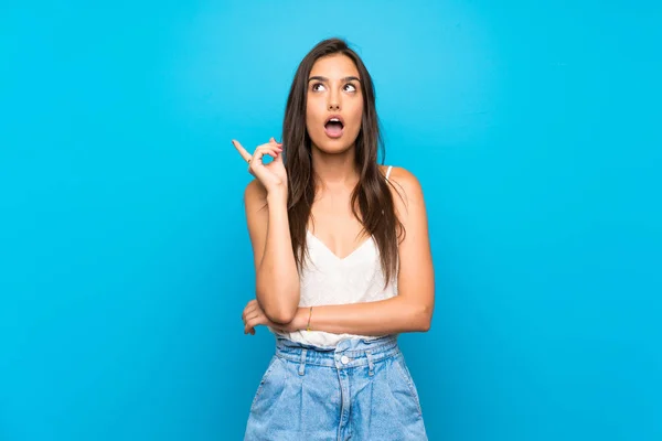 Jovem Mulher Sobre Fundo Azul Isolado Pensando Uma Ideia Apontando — Fotografia de Stock