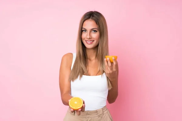 Fiatal szőke nő felett elszigetelt háttér kezében egy narancs — Stock Fotó