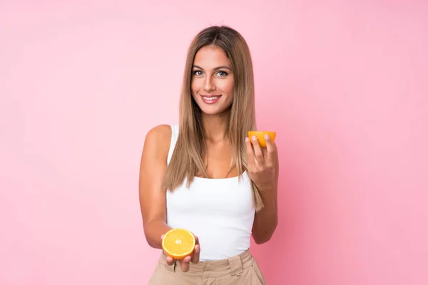 Jovem loira sobre fundo isolado segurando uma laranja — Fotografia de Stock