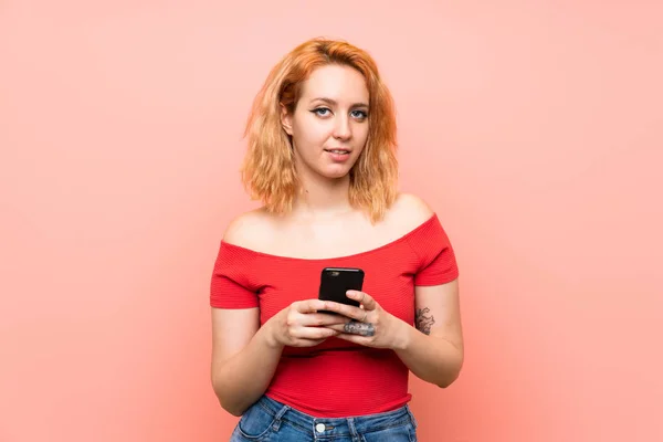 Giovane Donna Sfondo Rosa Isolato Invio Messaggio Con Cellulare — Foto Stock