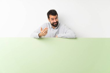 Sakallı genç, yakışıklı bir adam elinde kocaman boş bir pankartla bizi davet ediyor. Gelmene sevindim.