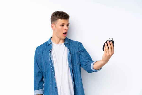 Joven Hombre Guapo Sobre Fondo Blanco Aislado Sosteniendo Reloj Despertador —  Fotos de Stock