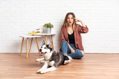 İçeride köpeğiyle yerde oturan genç bir kız çözümün ne olduğunu anlamaya çalışıyor.