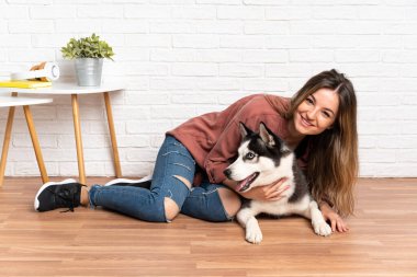 Genç ve güzel bir kadın. İri köpeğiyle içeride yerde oturuyor.