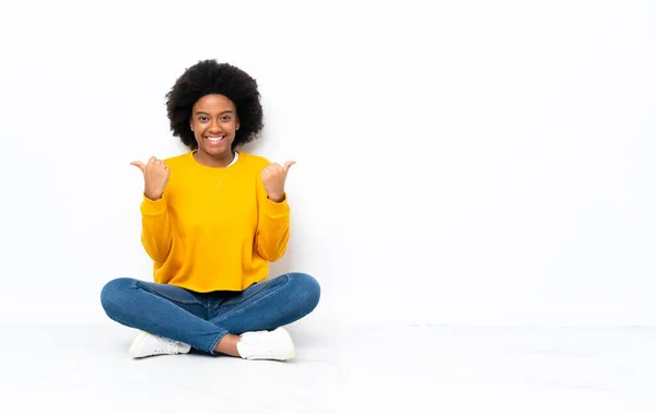 Молода Афро Американська Жінка Сидить Підлозі Пальцями Вгору Жест Посміхається — стокове фото