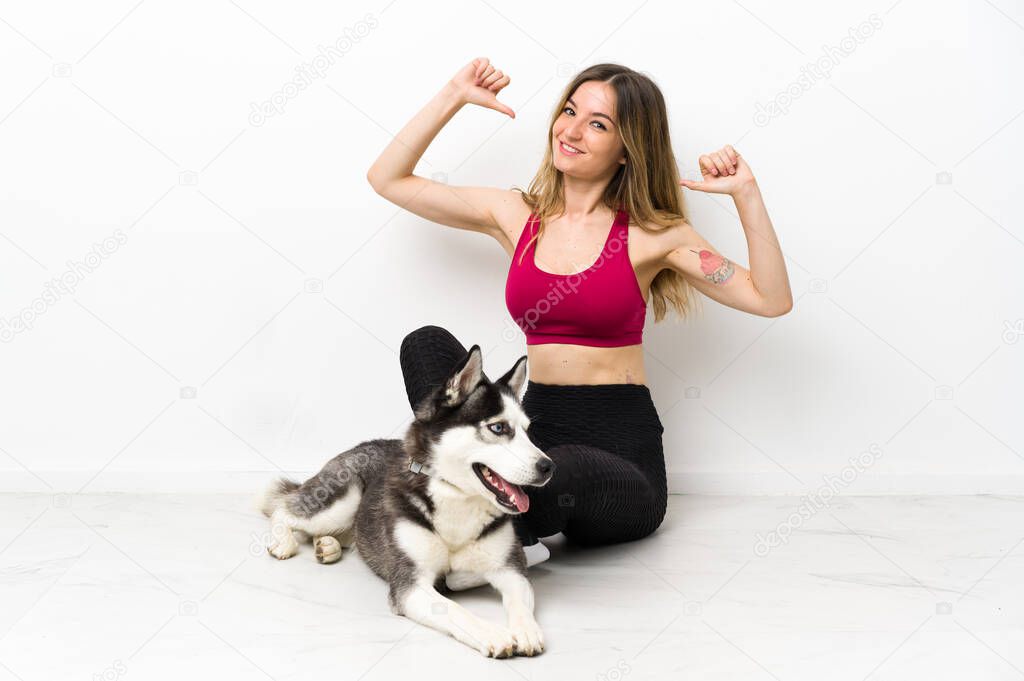 Young sport girl with her dog sitting on the floor proud and self-satisfied