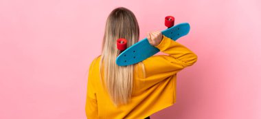 Genç sarışın kadın pembe arka planda izole edilmiş ve arka planda paten kayıyor.