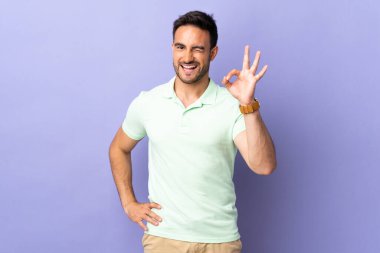 Mor arka planda izole edilmiş genç yakışıklı parmaklarıyla işaret ediyor.