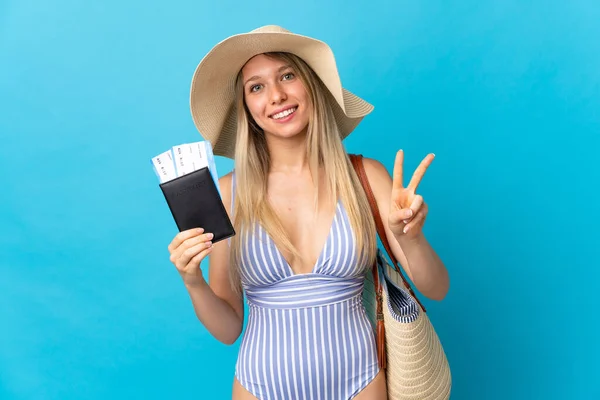 Jonge Blonde Vrouw Met Een Paspoort Geïsoleerd Blauwe Achtergrond Glimlachen — Stockfoto