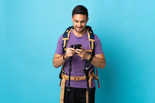 Jovem Caucasiano Com Mochila Postes Trekking Isolados Fundo Azul Enviando — Fotografia de Stock