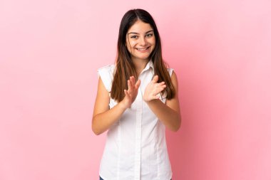 Pembe arka planda izole edilmiş genç beyaz kadın bir konferanstan sonra alkışlıyor.