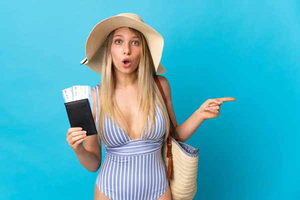Jonge Blonde Vrouw Met Een Paspoort Geïsoleerd Blauwe Achtergrond Verrast — Stockfoto