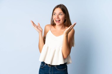 Genç Litvanyalı kadın mavi arka planda izole edilmiş ve yüzünde sürpriz bir ifade var.