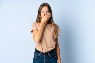 Genç Litvanyalı kadın mavi arka planda izole edilmiş, ağzı elle kapatılmış.