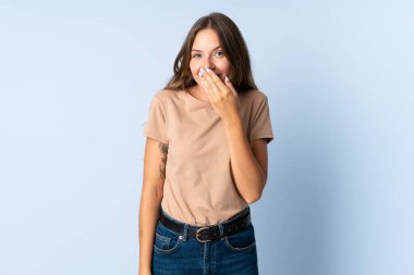 Genç Litvanyalı bir kadın mavi arka planda izole edilmiş mutlu ve gülümseyen bir ağızla elini kapatıyor.