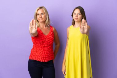 Anne ve kızı mor arka planda izole edilmiş. Yanlış bir durum olduğunu düşünen bir jesti engelliyor.